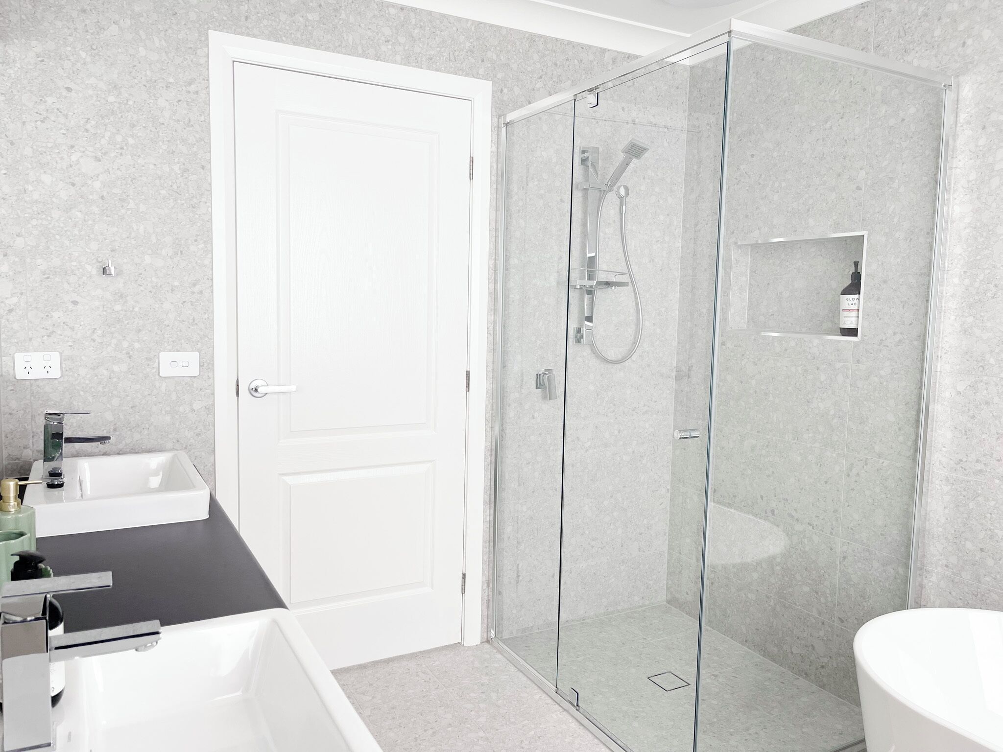 A modern bathroom with a glass-enclosed shower, a white sink, and a toilet.
