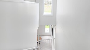 Un intérieur blanc avec une fenêtre, une porte et un escalier.