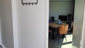 Un corridoio con un appendiabiti, una sala da pranzo con tavolo e sedie, e un rilevatore di fumo a soffitto.