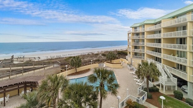 A beachfront hotel with multiple balconies, a swimming pool, and a beach view. - Oceanfront 3 Bdrm Getaway to the Beach Sleeps 6 (Pawleys Island)