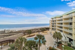 Un hôtel en bord de mer doté de nombreux balcons, d’une piscine et offrant une vue sur la plage.