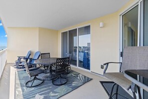 Un balcon avec une table et des chaises, une vue sur la mer et une porte-fenêtre coulissante.