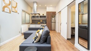 A modern living room with a grey sofa, a round coffee table, and a view into the kitchen area.