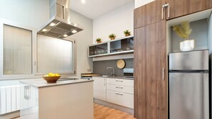 A modern kitchen with a central island, wooden cabinets, and a stainless steel refrigerator.