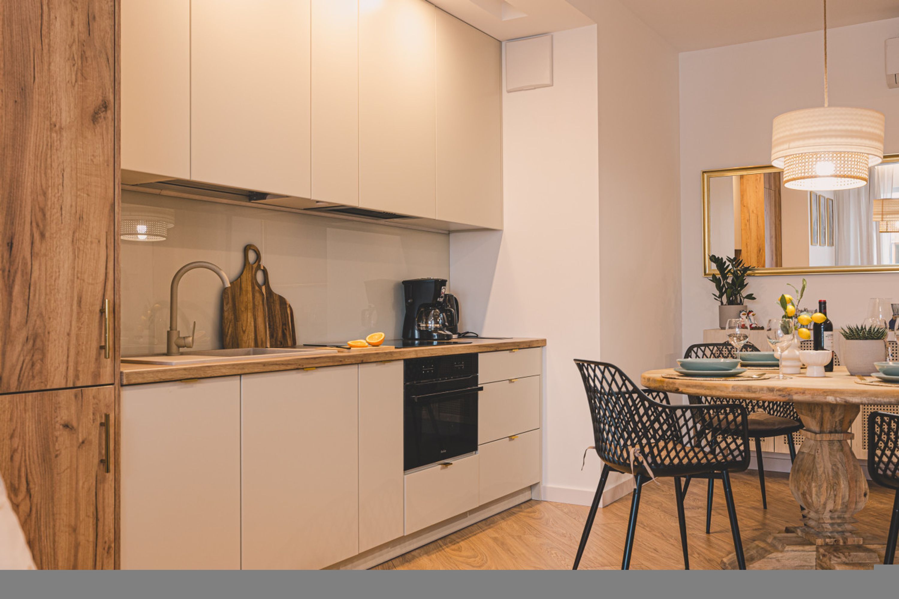 Une cuisine moderne avec des meubles blancs, un plan de travail en bois et un coin repas comprenant une table ronde et des chaises.