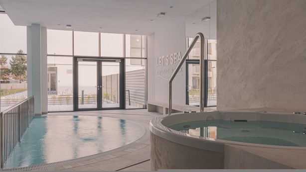 A modern indoor swimming pool area with a large glass door leading outside, a hot tub, and a sign that reads "LET'S SEA BALTIC SEA". - Laguna Basen SPA Przy pla y Gara Wifi (Mielno)