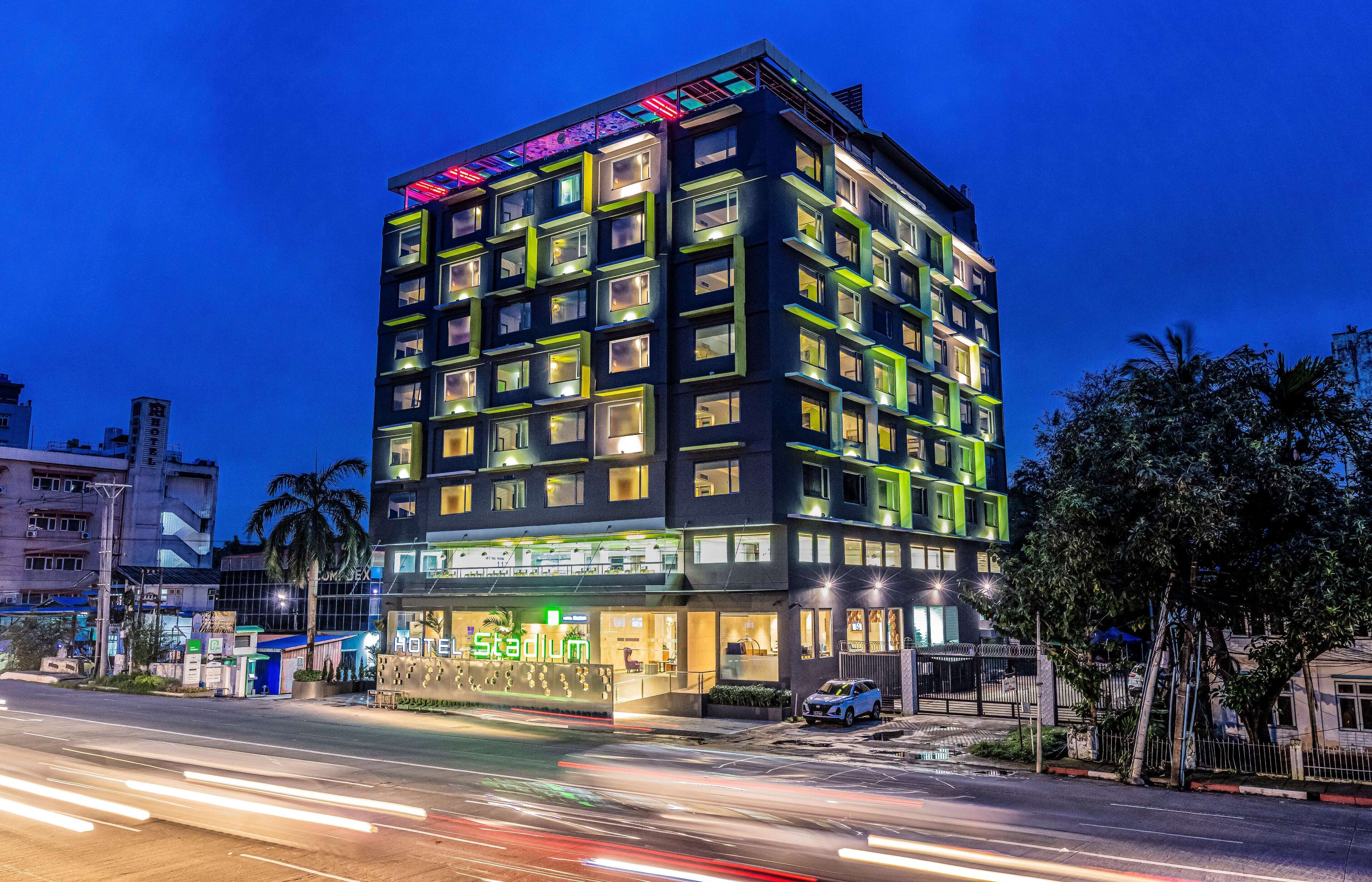 Un hotel de varios pisos con diseño moderno, que destaca un letrero grande que dice 'Hotel Stadium' en la entrada.