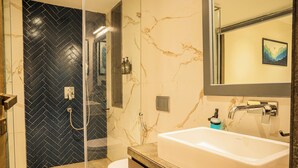 A modern bathroom with a black and white marble wall, a white sink, and a glass shower enclosure. - Marvelous villa with AC in Saligao - 5 bedrooms available (Saligao)