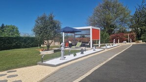 Un giardino con un gazebo, statue e un vialetto lastricato.