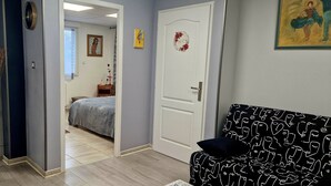 Una stanza con un letto, un divano, un tavolo da pranzo e un vaso con piante essiccate.