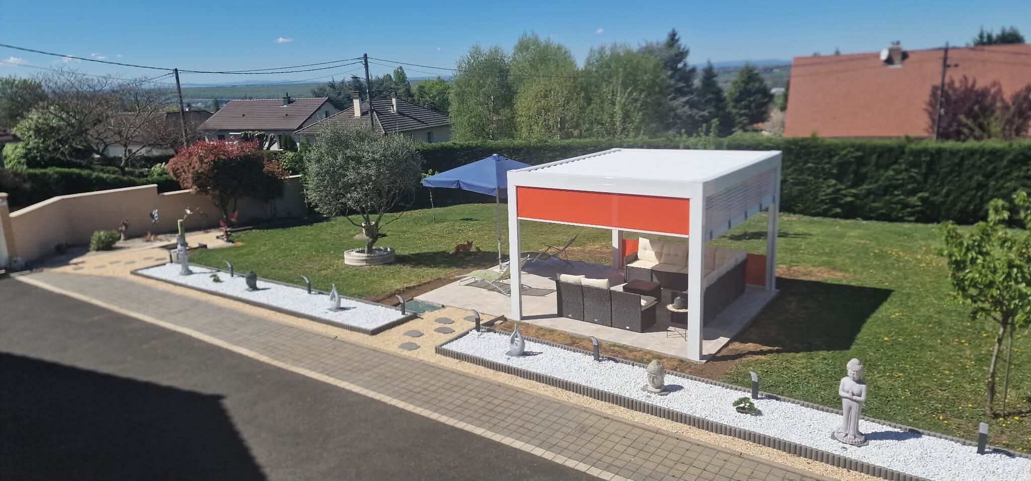 Et moderne udendørs opholdsområde med en hvid og orange struktur, omgivet af en anlagt have med et lille bassin og dekorative detaljer.