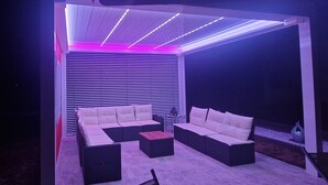 Un'area salotto esterna con divano e poltrone, un tavolo e un elemento decorativo.