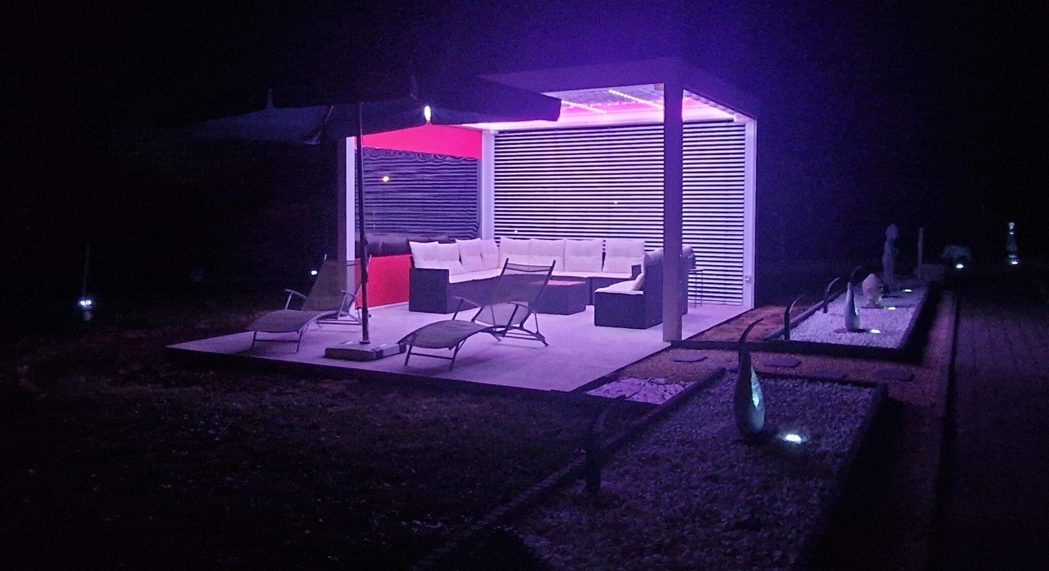 Un espace de détente extérieur moderne, doté de sièges et d’un mur d’accent rouge.