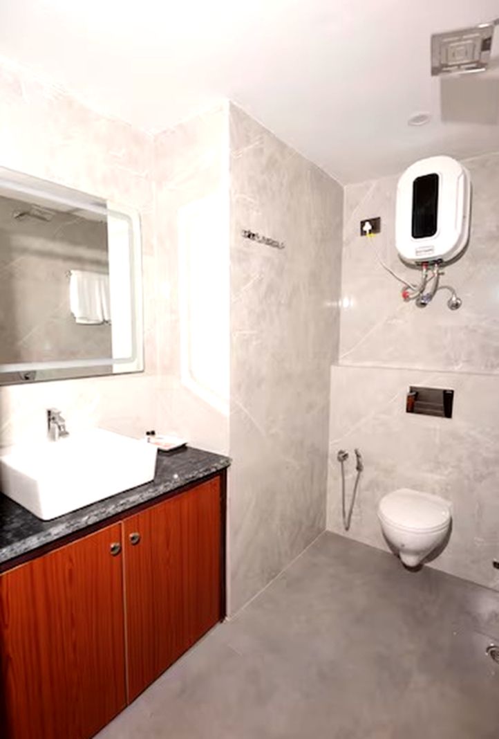 A modern bathroom with a large mirror, a sink, and a toilet.