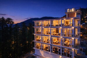 A multi-story hotel with balconies, large windows, and a mountainous backdrop. - White Castle Himalayan View by Lavenders Hotels (Shimla)