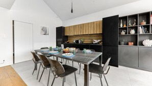 A modern kitchen with a dining area, featuring a black and white color scheme, wooden cabinets, and a variety of kitchen appliances.