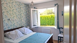 A bedroom with a bed, a window with curtains, a radiator, and a chair. - House 400m from the beach, for 6 people (Penvénan)