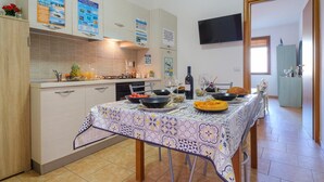 A modern kitchen with a dining table set for a meal, featuring a variety of dishes and drinks. - Wavefront San Foca (Melendugno)
