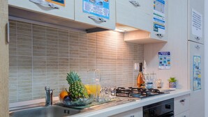 A modern kitchen with a stainless steel sink, a gas stove, and a tiled backsplash. - Wavefront San Foca (Melendugno)