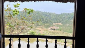A room with a bed, a view of a river, and a thatched roof. - Ban Lien Homestay (Ban Lien)