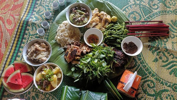 Un repas traditionnel composé de riz, de viande, de légumes et d’assaisonnements, servi sur un tapis tressé.