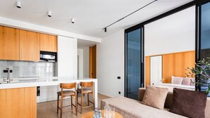 A modern kitchen with wooden cabinets, a central island, and a dining area with chairs. - Boulevard 129 (Tashkent)