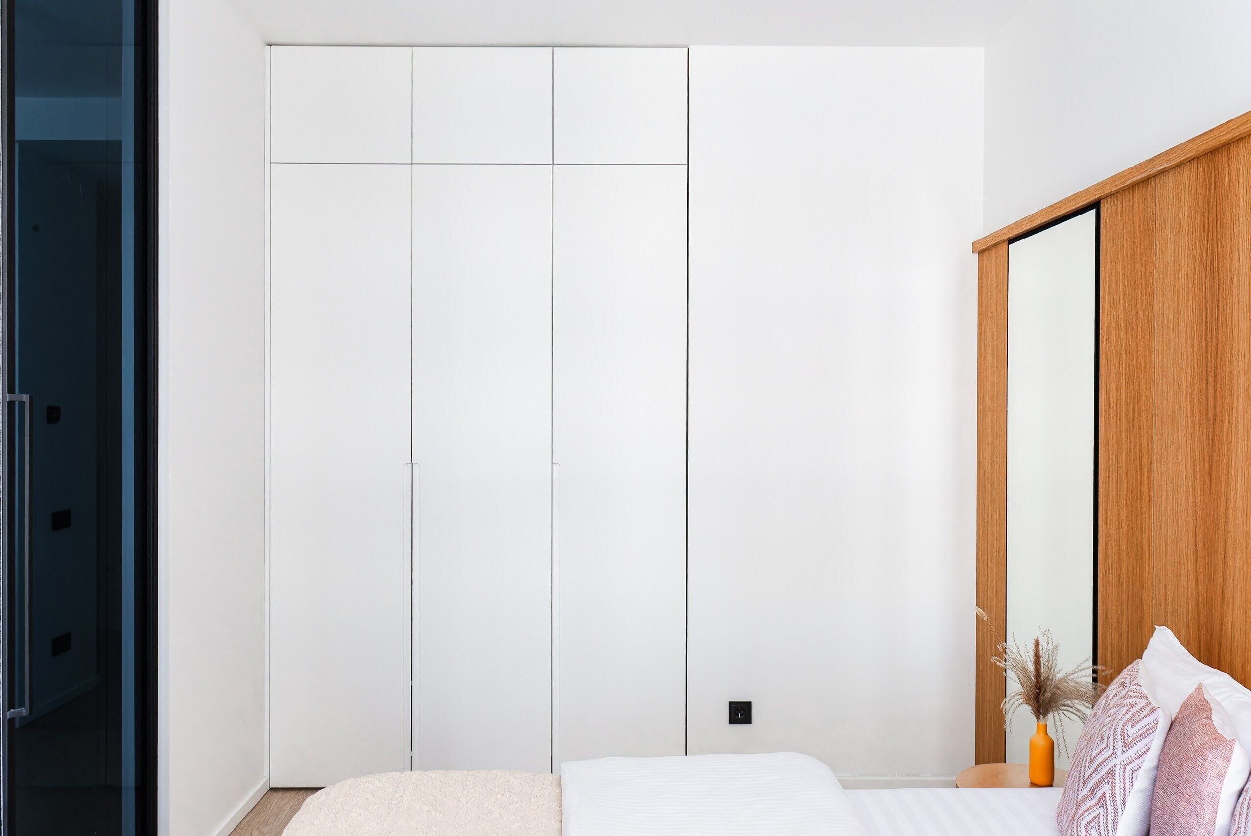 Ein Schlafzimmer mit einem Bett, einem Holzschrank und einem Spiegel.