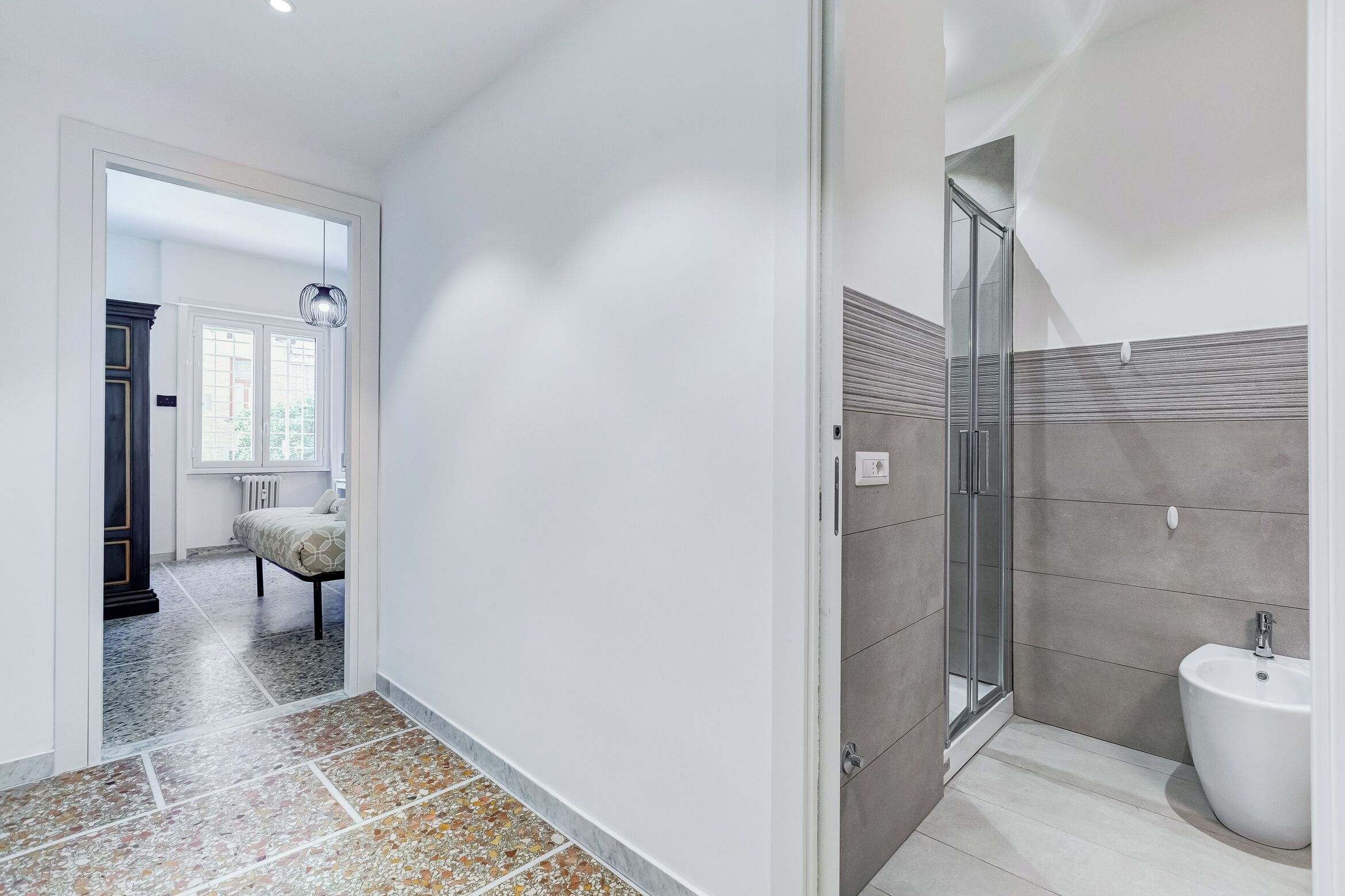 A modern bathroom with a glass shower, a white sink, and a tiled floor.