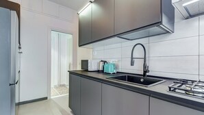 A modern kitchen with grey cabinets, a black sink, and a teal kettle. - Gianicolo Apartment with Terrace (Rome)