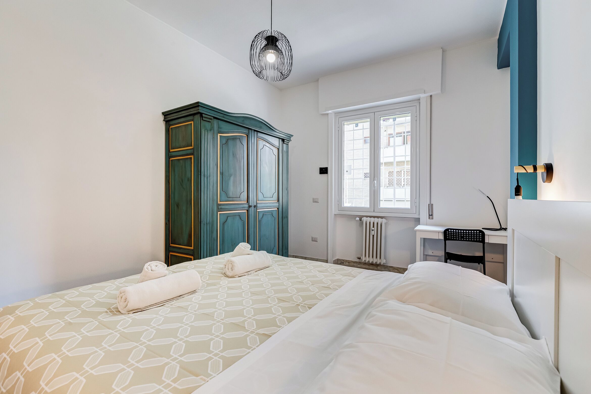 Una camera d'albergo con un letto, una scrivania, un armadio e una finestra.