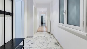 A hallway with a marble floor, white walls, and a black bench. - Gianicolo Apartment with Terrace (Rome)