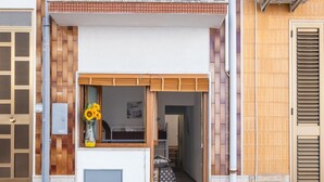A modern building entrance with a wooden door, a small window with a flower vase, and a visible interior hallway. - On The Sea San Foca wifi Ac (Melendugno)