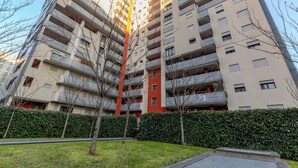 A high-rise residential building with multiple balconies, a well-maintained lawn, and a hedge. - notaMi - UniGarden - Bicocca District (Milan)
