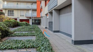 A multi-story residential building with balconies, a pathway lined with greenery, and a clear sky. - notaMi - UniGarden - Bicocca District (Milan)