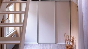 Ein Schlafzimmer im Loft-Stil mit einem Etagenbett, einer Leiter, einem gewobenen Korb und einem Oberlicht.