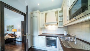A modern kitchen with white cabinetry, stainless steel appliances, and a dark wooden countertop.