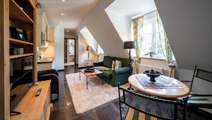 Een modern loft appartement met een eetgedeelte, een groene bank en een keuken op de achtergrond.