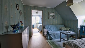 A cozy room with a sloped ceiling, a sofa, a table, and a kitchen area with a counter and cabinets.