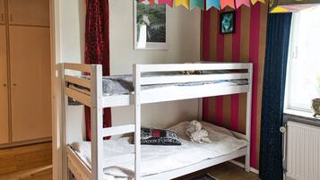Cozy room with a bunk bed setup, featuring a lower and upper bunk, a wardrobe, and a window with curtains.