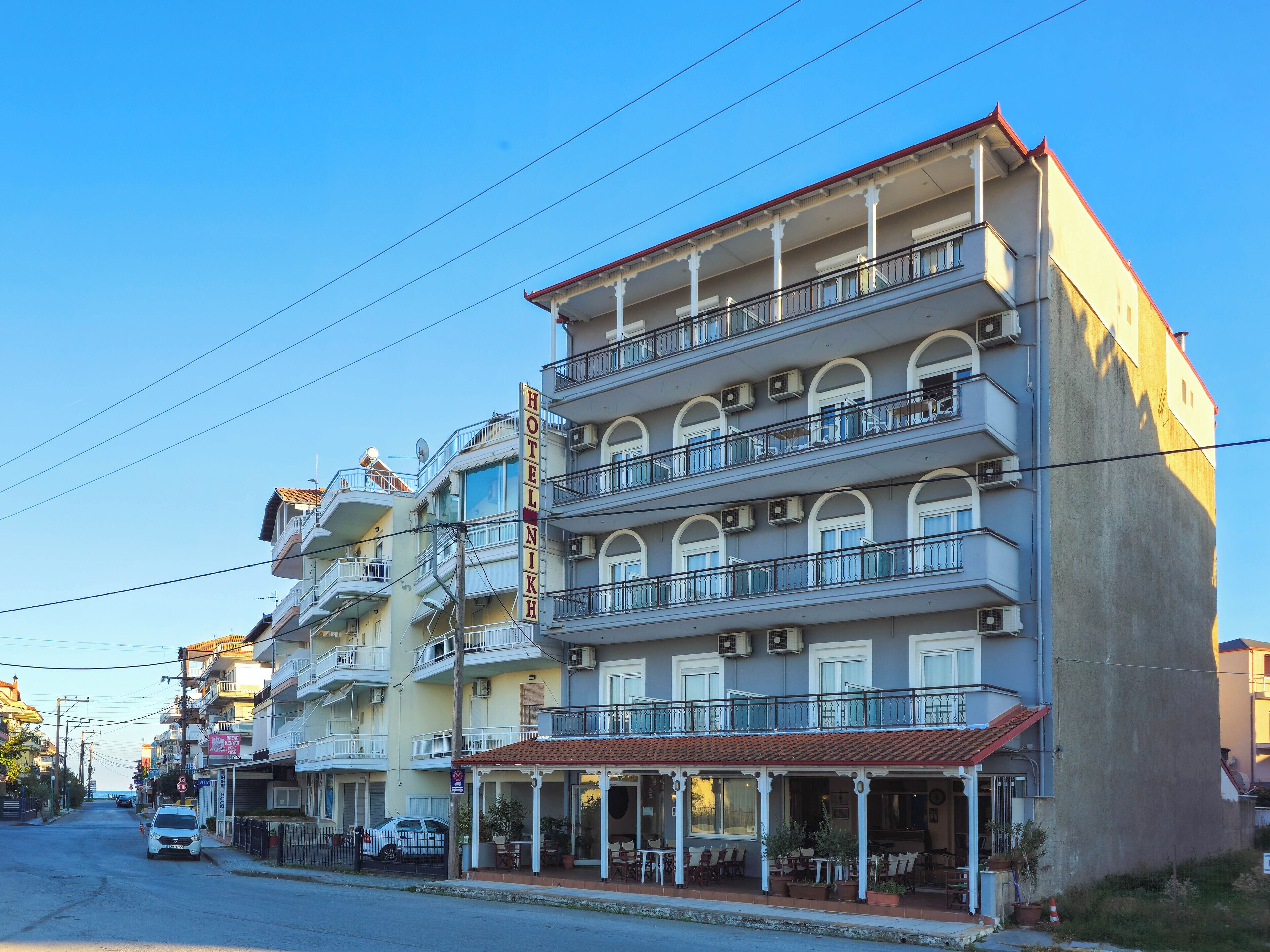 A multi-story hotel with balconies, a covered outdoor seating area, and a visible entrance.