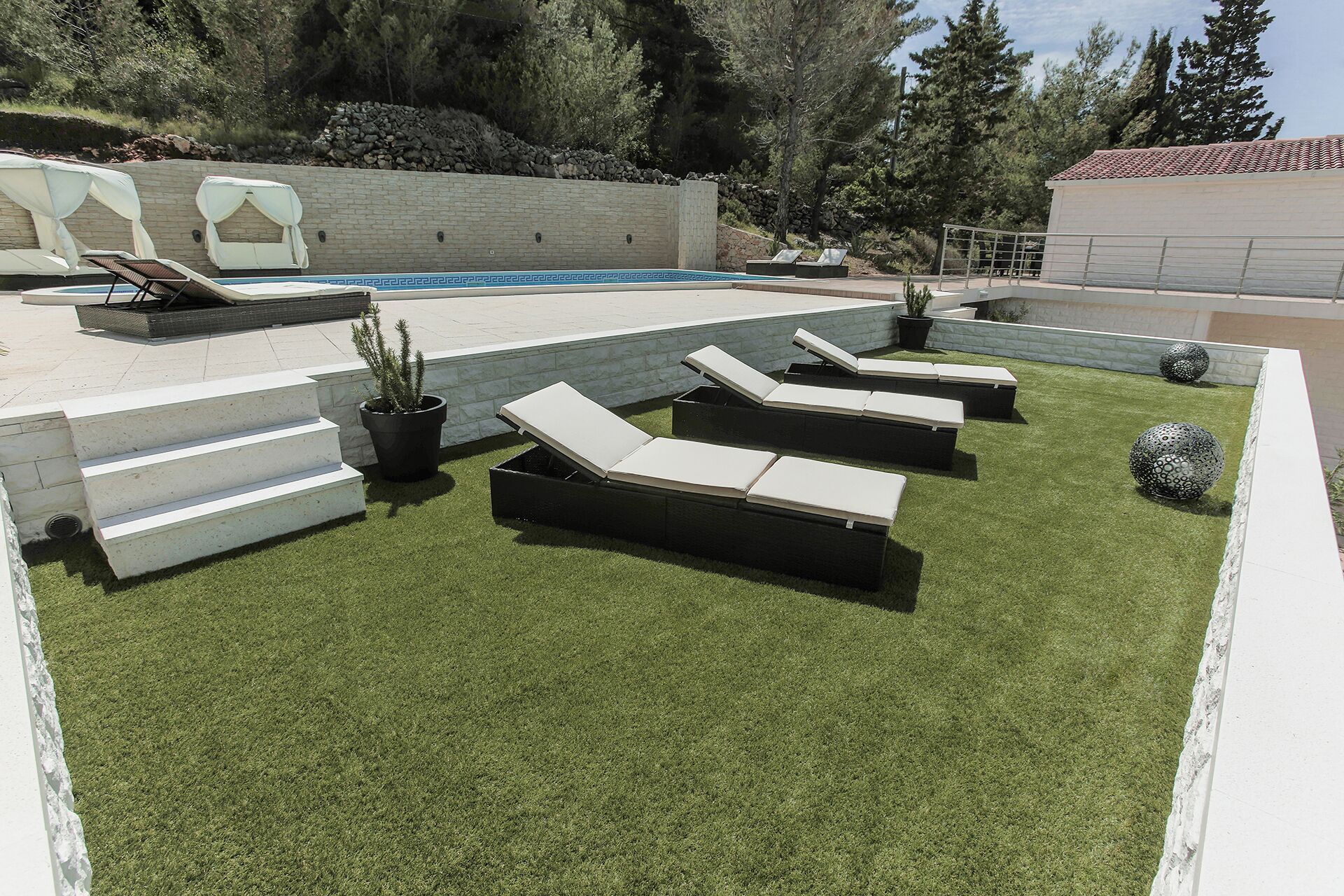Un área junto a la piscina con sillones de descanso, una piscina pequeña y un muro de piedra.