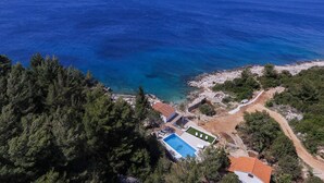 An aerial view of a coastal property with a swimming pool, a small building, and a rocky beach area. - "Villa Mendes" - new seafront villa with a swimming pool (Zastražišće)