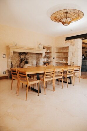 A dining area with a wooden table and chairs, a stone fireplace, and shelves with kitchenware. - Intimate estate in the heart of Drôme Provençale (la garde adhemar)