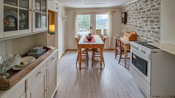 A kitchen with a wooden table, white cabinets, and a stone wall. - Nice home in Hovsherad with WiFi (Hovsherad)