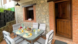 Une terrasse extérieure avec un mur en pierre, une porte en bois et une table dressée pour le petit-déjeuner.