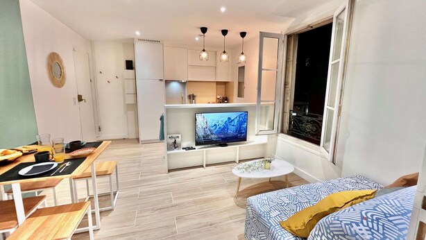 A modern living room with a sofa, dining table, and kitchen area. - Le Victor Hugo - Clichy-la-Garenne (Clichy)