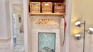 A hallway with a wooden shelf holding baskets, a framed artwork of a bicycle, and a mirror.