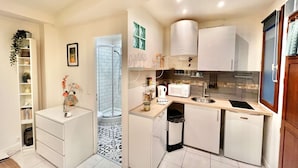 A compact kitchen with white cabinets, a microwave, a sink, and a small refrigerator.