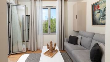 Una sala de estar moderna con un sofá gris, una mesa de centro de madera y un ventanal que da a un balcón.