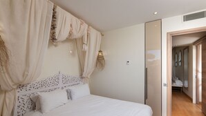 Une chambre à coucher avec un lit, des rideaux et une porte donnant sur une autre pièce.